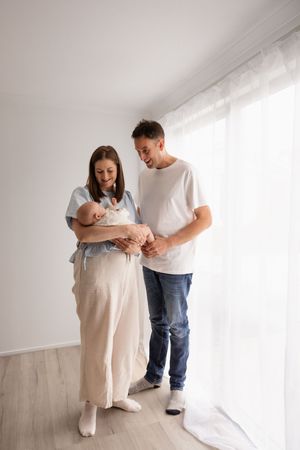 Mum holding her 10 week baby during newborn session in Bishopdale studio aand dad looking at baby,