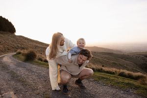 Dad giving son a piggy back ride and mum leaning in laughing during sunset family/ maternity session at Port Hills