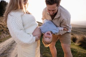 Dad putting son upside down near mums bump during sunset family/ maternity session at Port Hills