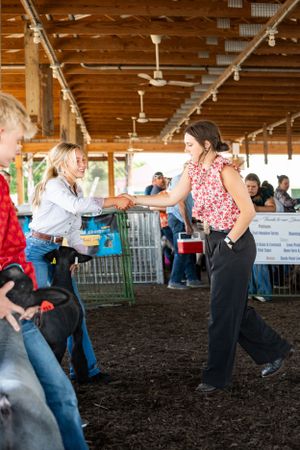 People dancing and moving in a covered barn arena during a country western event.