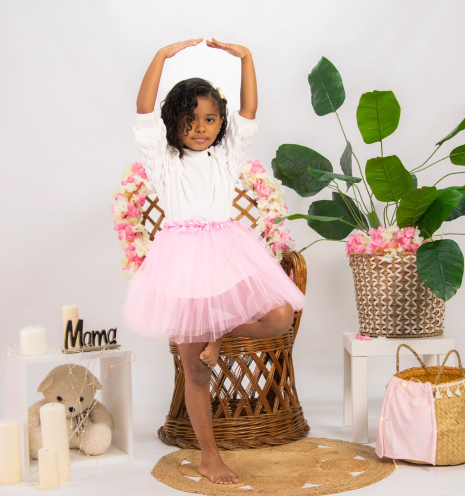 Pink tutu dress photoshoot setup with wicker basket and floral decorations against white backdrop.