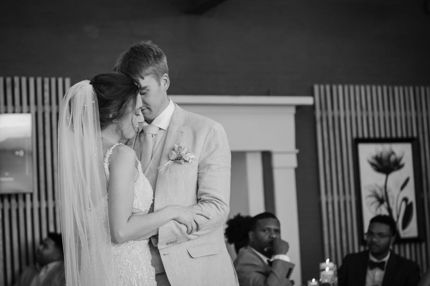 Black and white candid photo of tender wedding moment during ceremony.