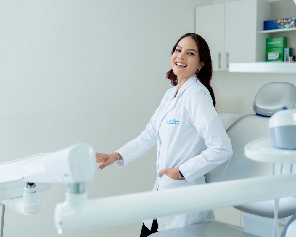 Healthcare professional in white lab coat smiling warmly in a modern medical office setting.