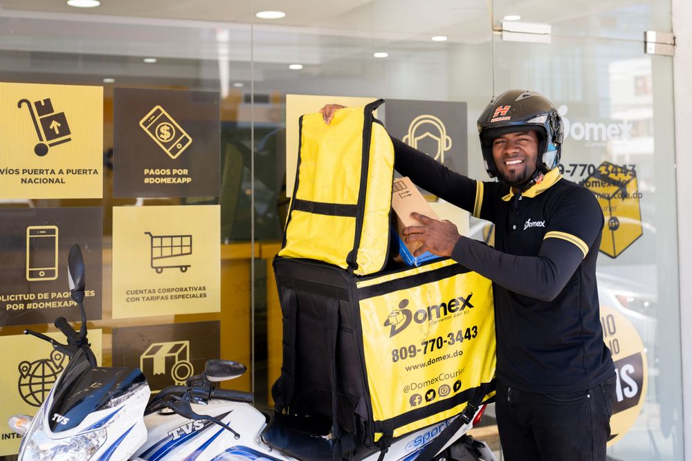 Delivery worker in uniform showcasing equipment and branded yellow backpack.