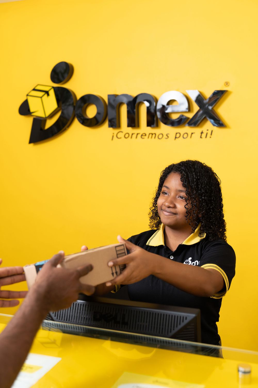 Employee handling package delivery at yellow-branded Jomex counter.