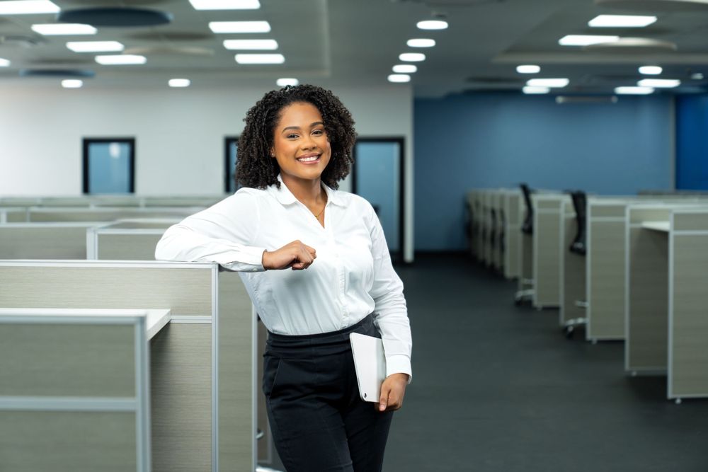 Professional in business attire standing confidently in modern office space.
