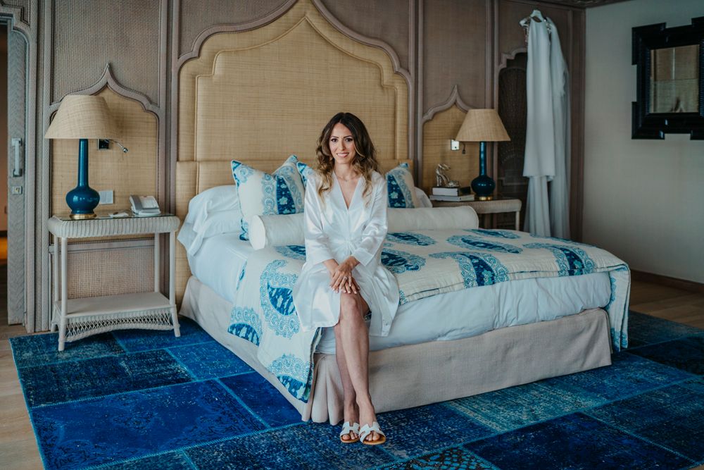 Elegant bedroom interior with blue carpet features a cream-colored upholstered bed and matching side tables with turquoise lamps.