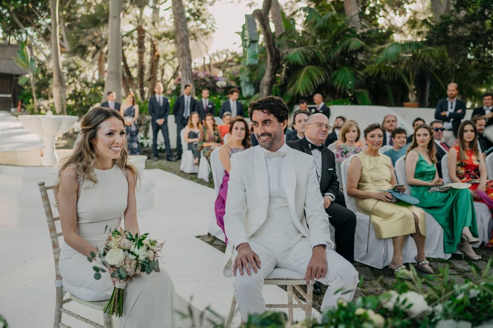 Wedding day ceremony outdoors with guests seated at garden venue as couple shares special moment at the altar.