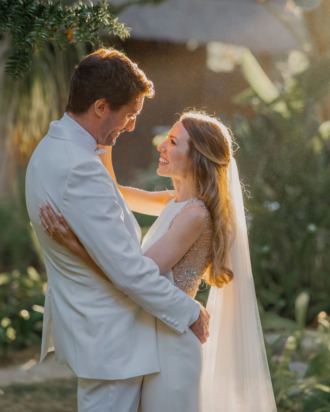 Wedding couple shares an intimate moment in a garden setting bathed in warm sunlight.