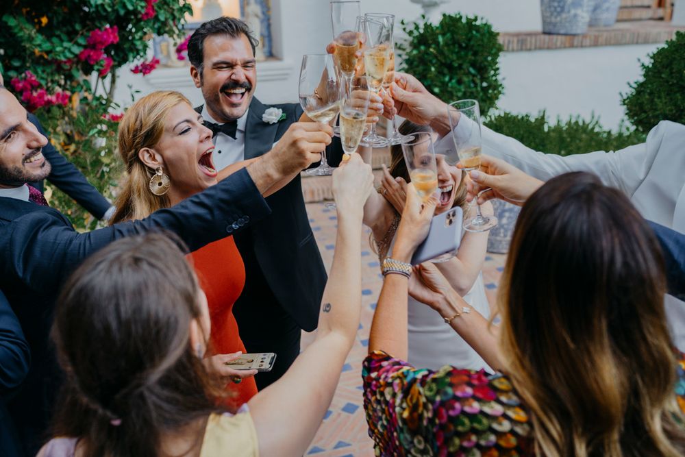 Wedding guests toasting with champagne glasses while celebrating outdoors.