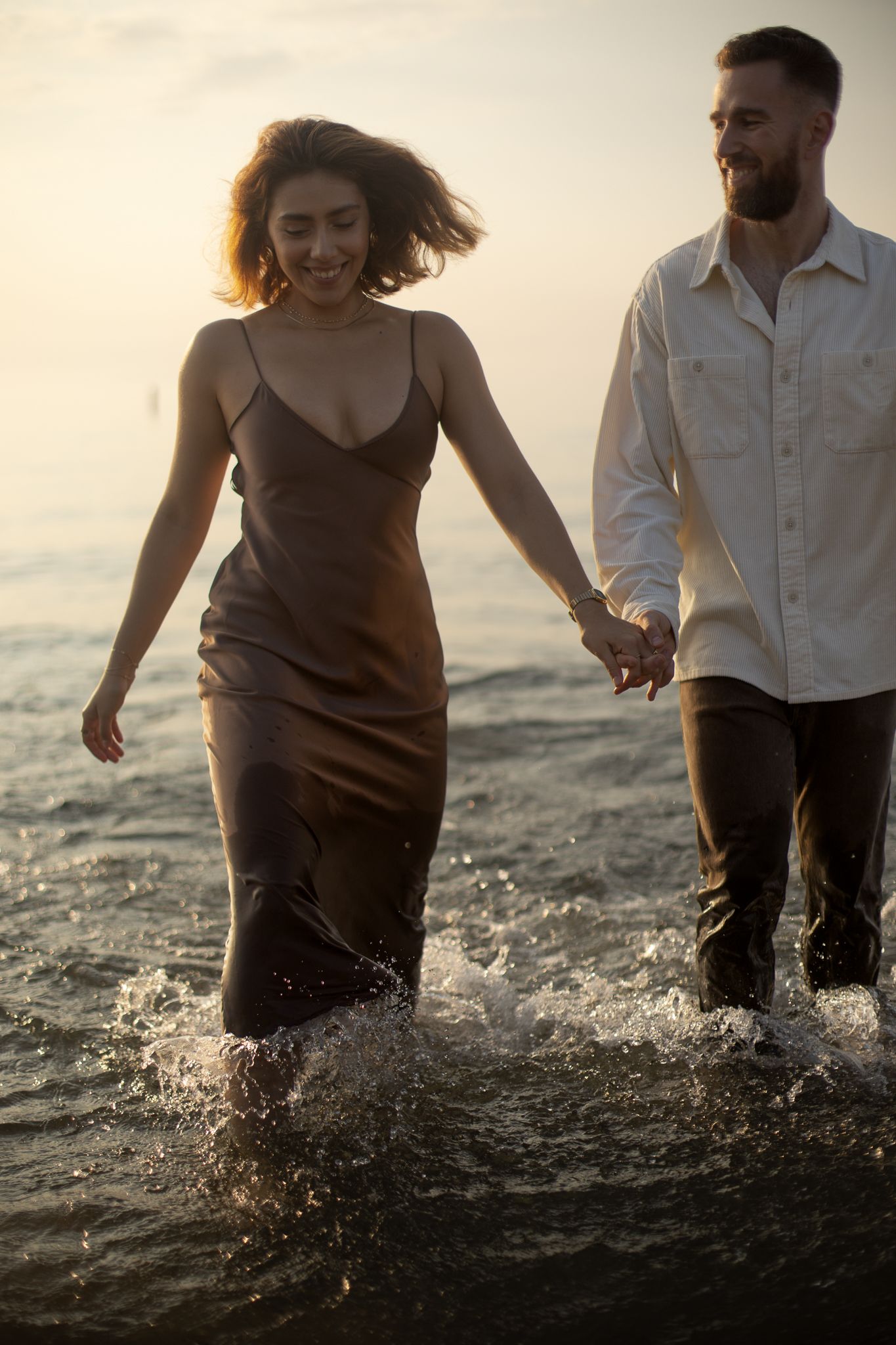 Couple getting of the lake with their clothes on and happy, in Scarborough beach, in Toronto, during sunrise