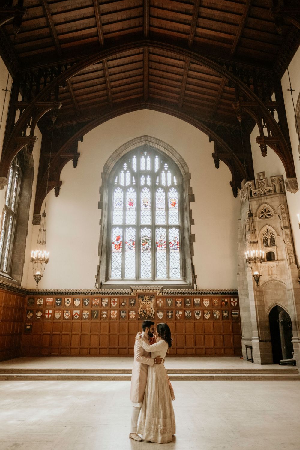 Gothic church interior with vaulted wooden ceiling, stained glass window and ornate wood paneling on the walls in romantic lighting.