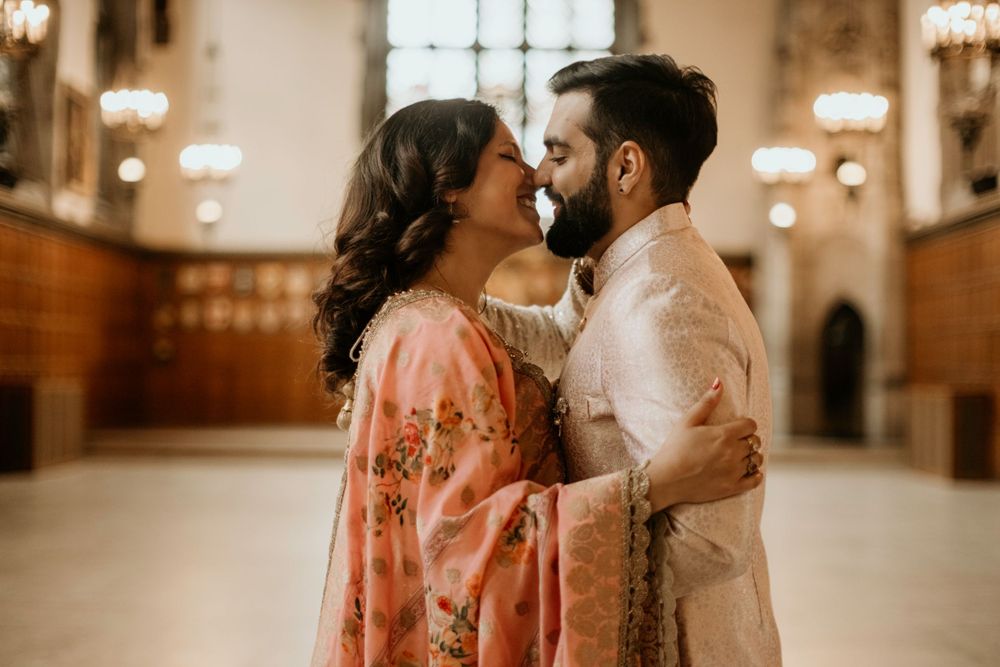 A romantic couple sharing an intimate moment in traditional South Asian attire inside an ornate building.