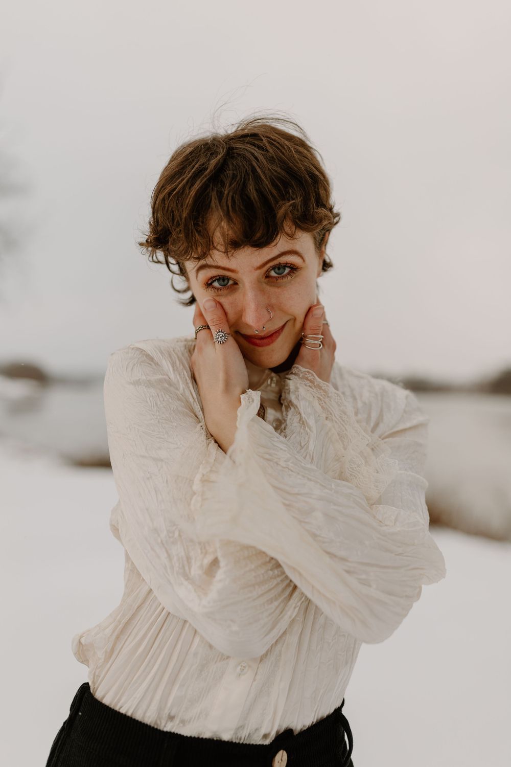 Portrait of person in white ruffled blouse against minimal light background.