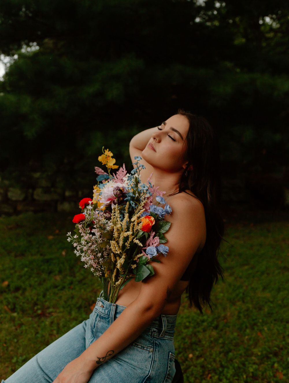Artistic portrait with wildflowers against a dark moody background in summer.
