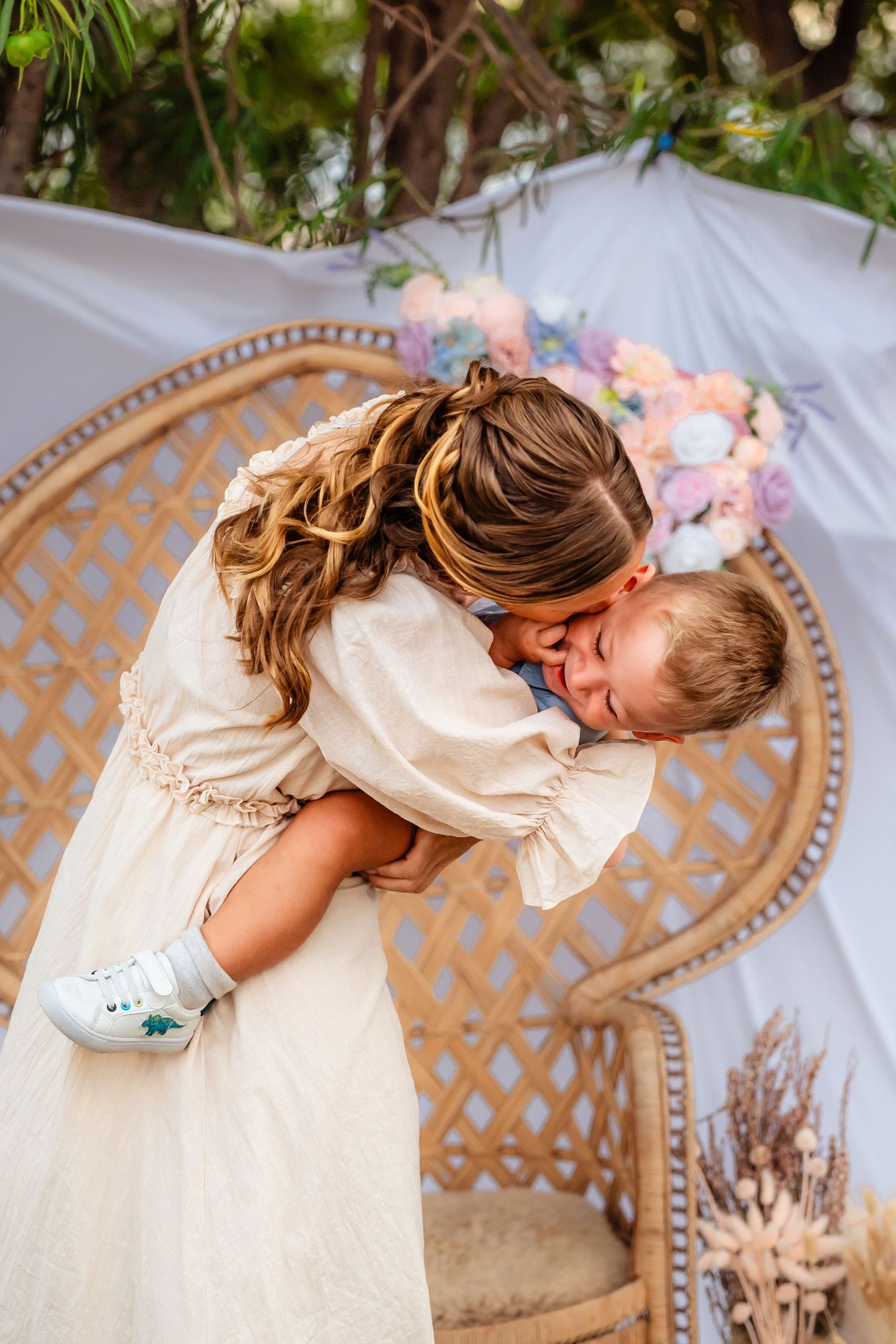 A tender moment between parent and child sharing a sweet kiss in a decorated outdoor setting.