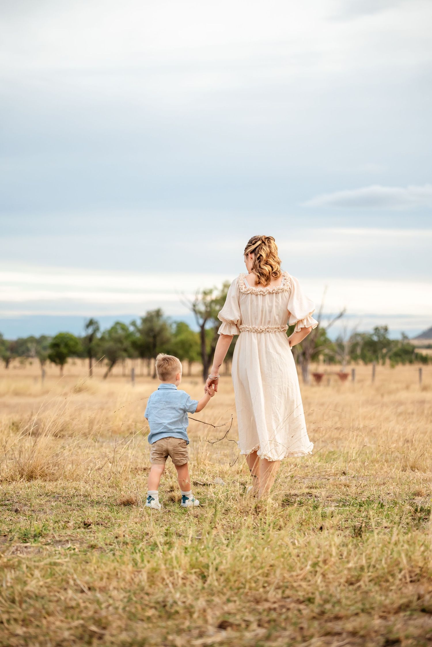 A dreamy silhouette of parent and child walking hand in hand through a golden field.