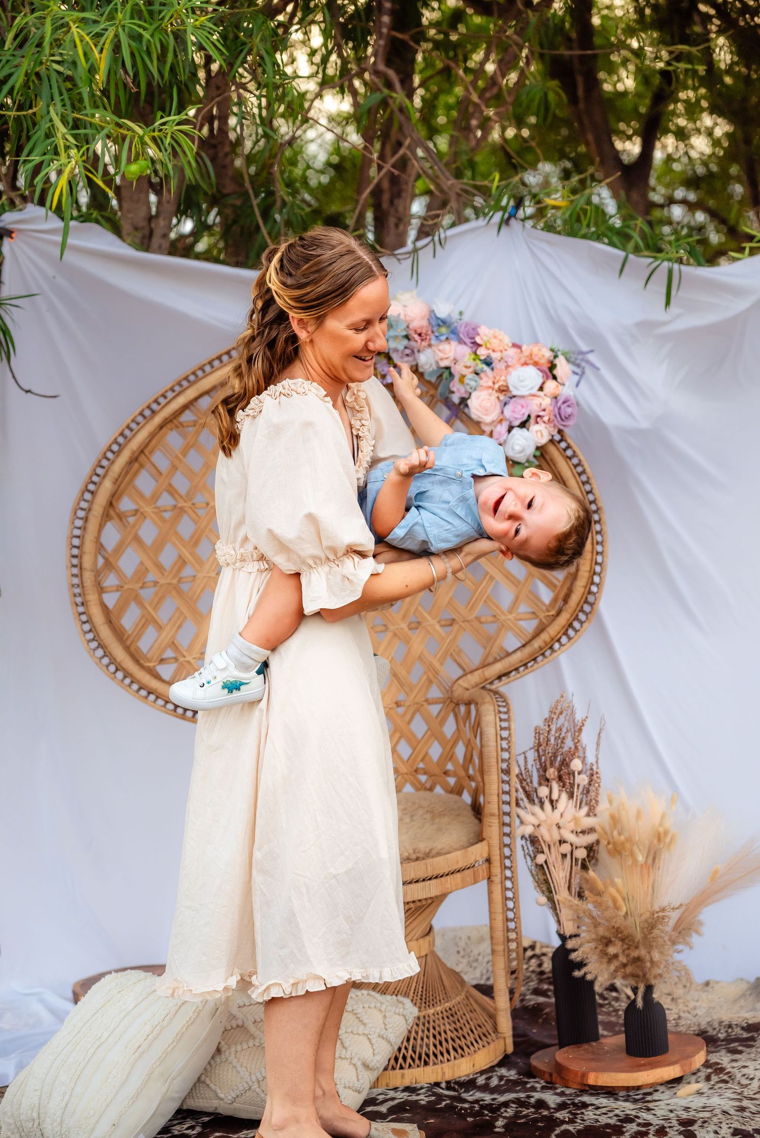 A playful moment between parent and child in front of a decorated outdoor backdrop.