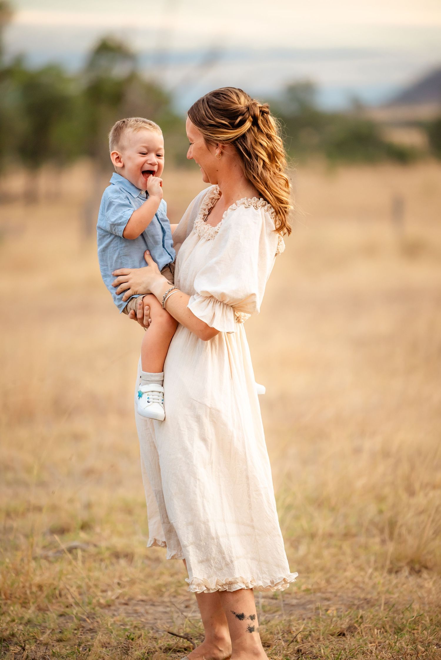 A candid portrait of parent and child laughing together in a sunlit field.