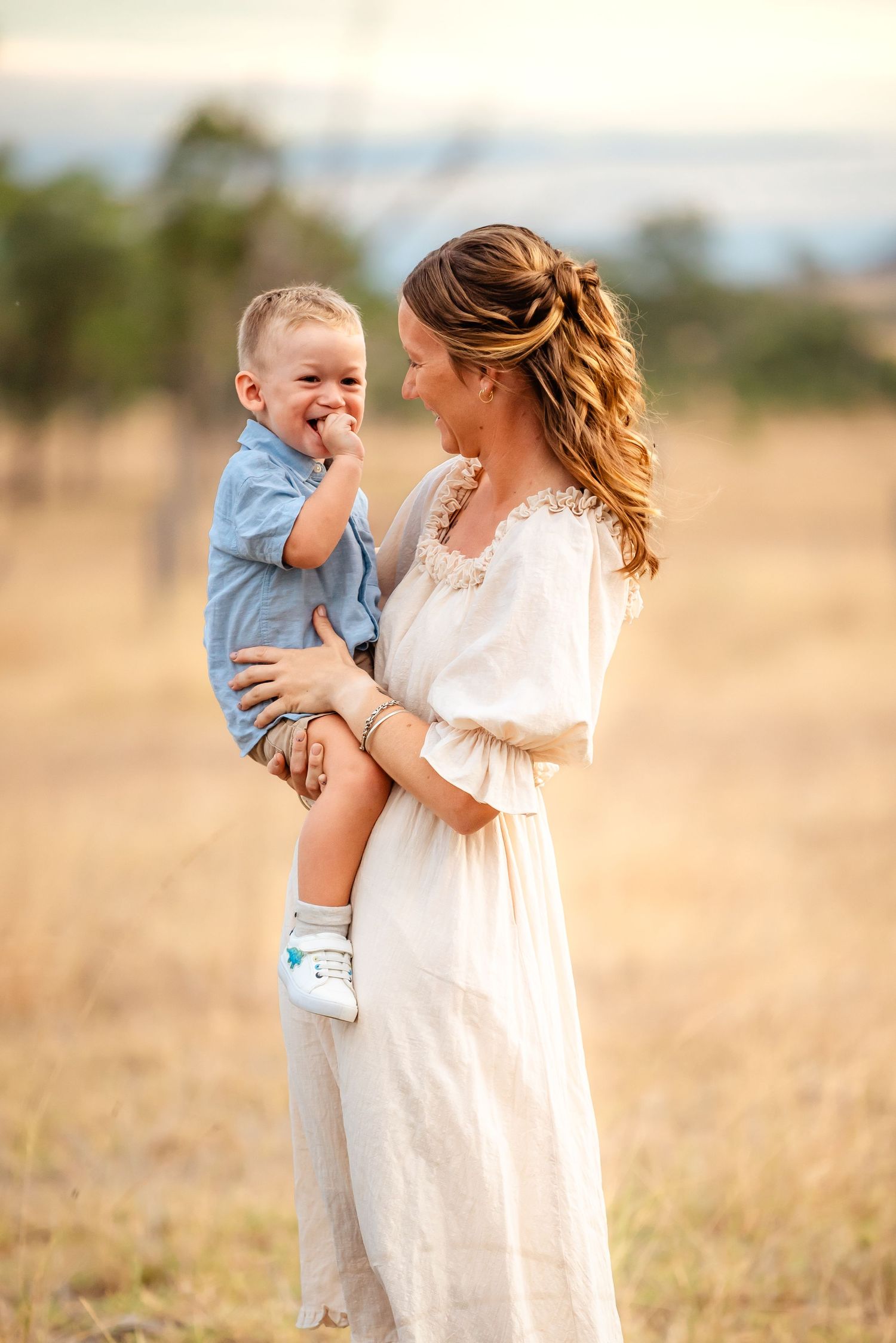 Mother and child share tender moments in a golden field during sunset.