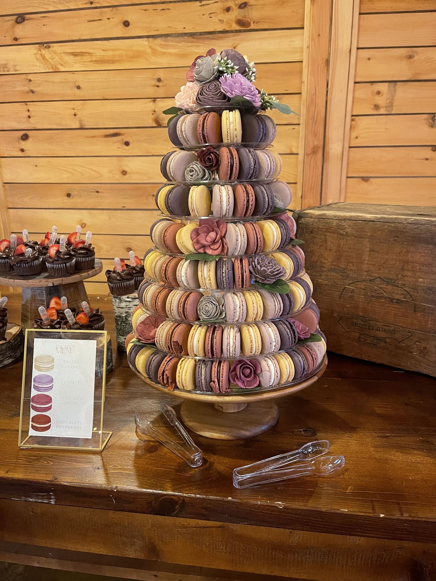 Tiered display of colorful French macarons on a rustic wooden stand.