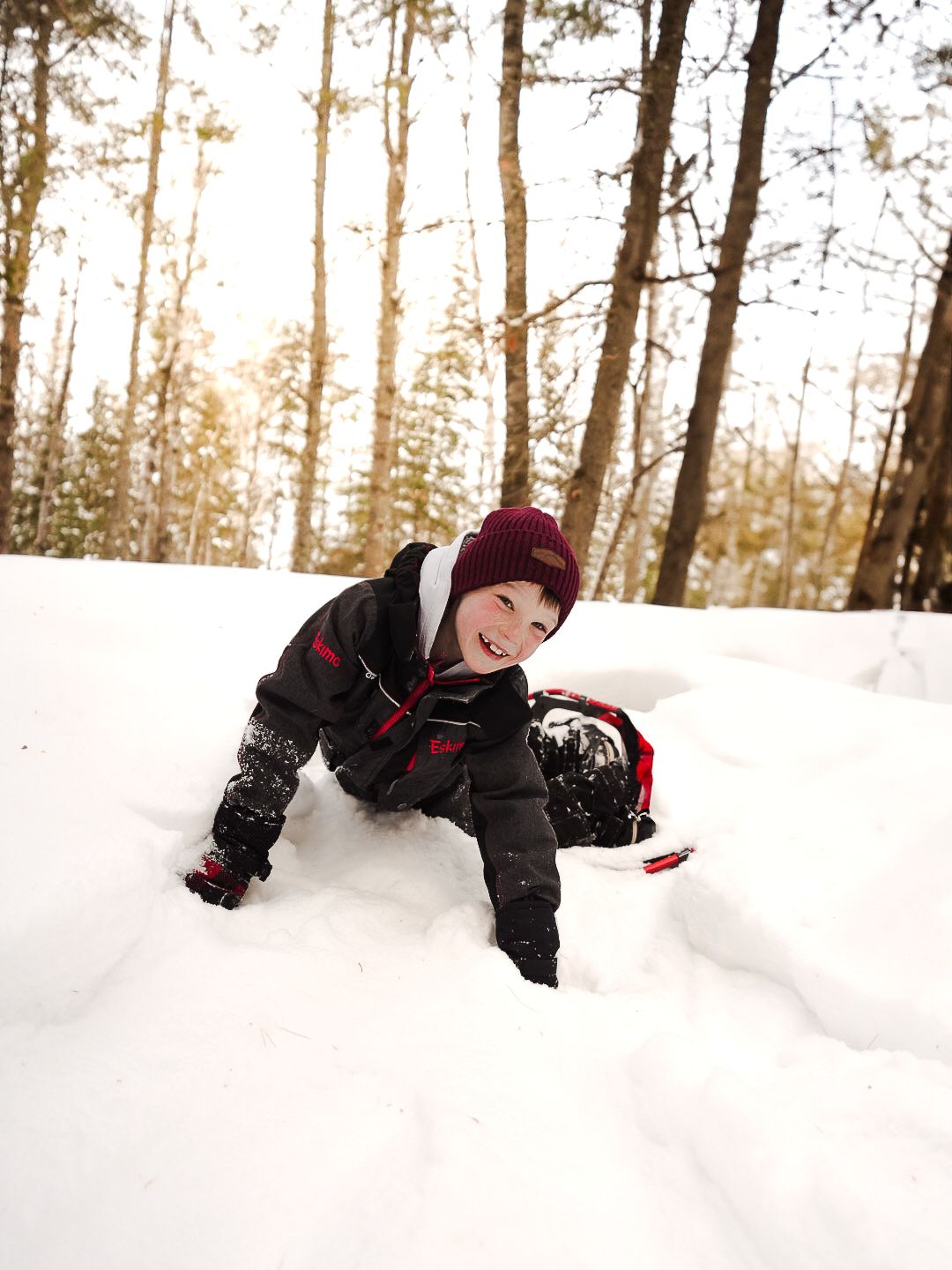 People playing and rolling in deep snow during winter forest adventure.