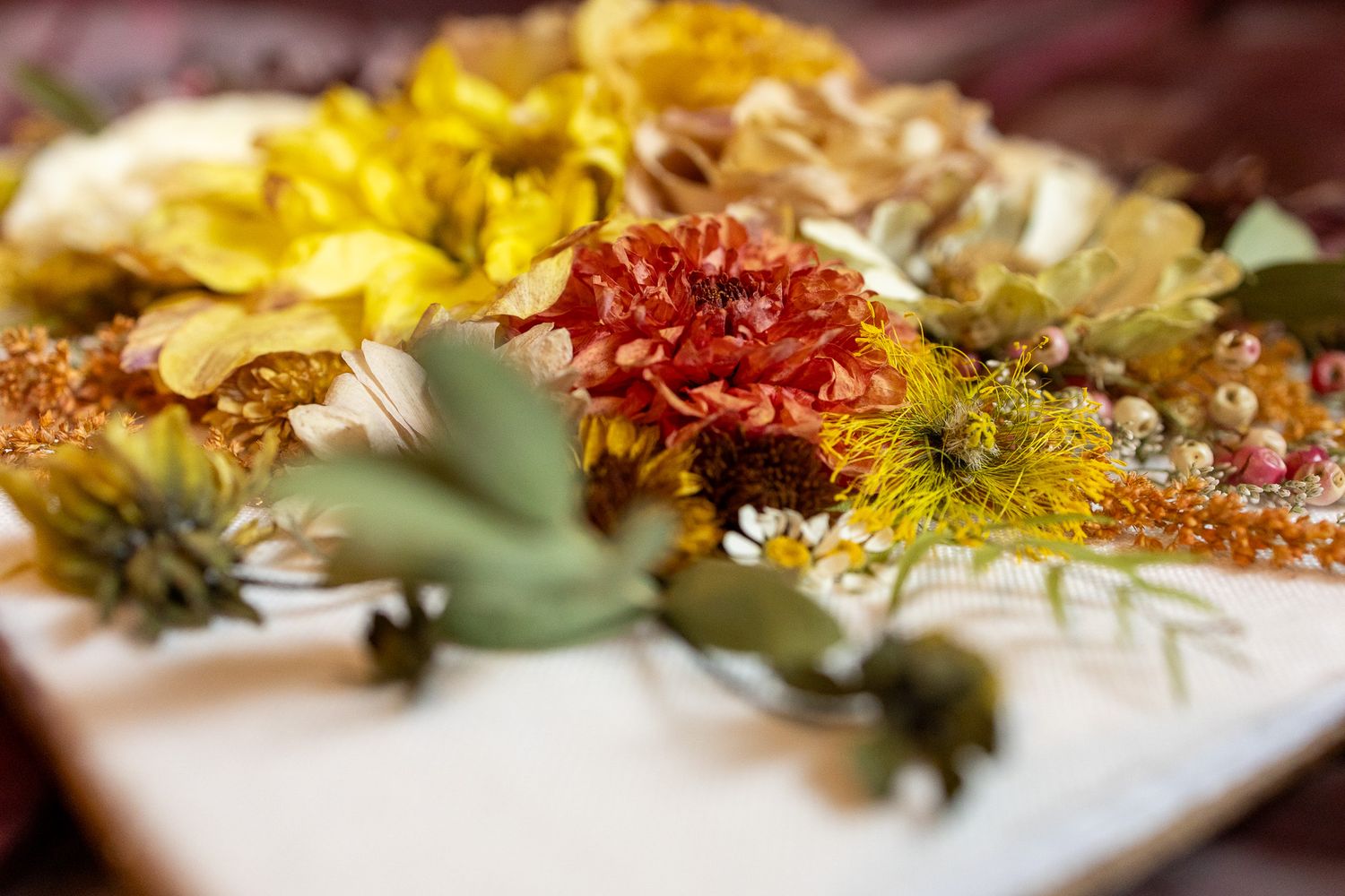Beautiful arrangement of colorful dried zinnias and baby's breath flowers in red and yellow.