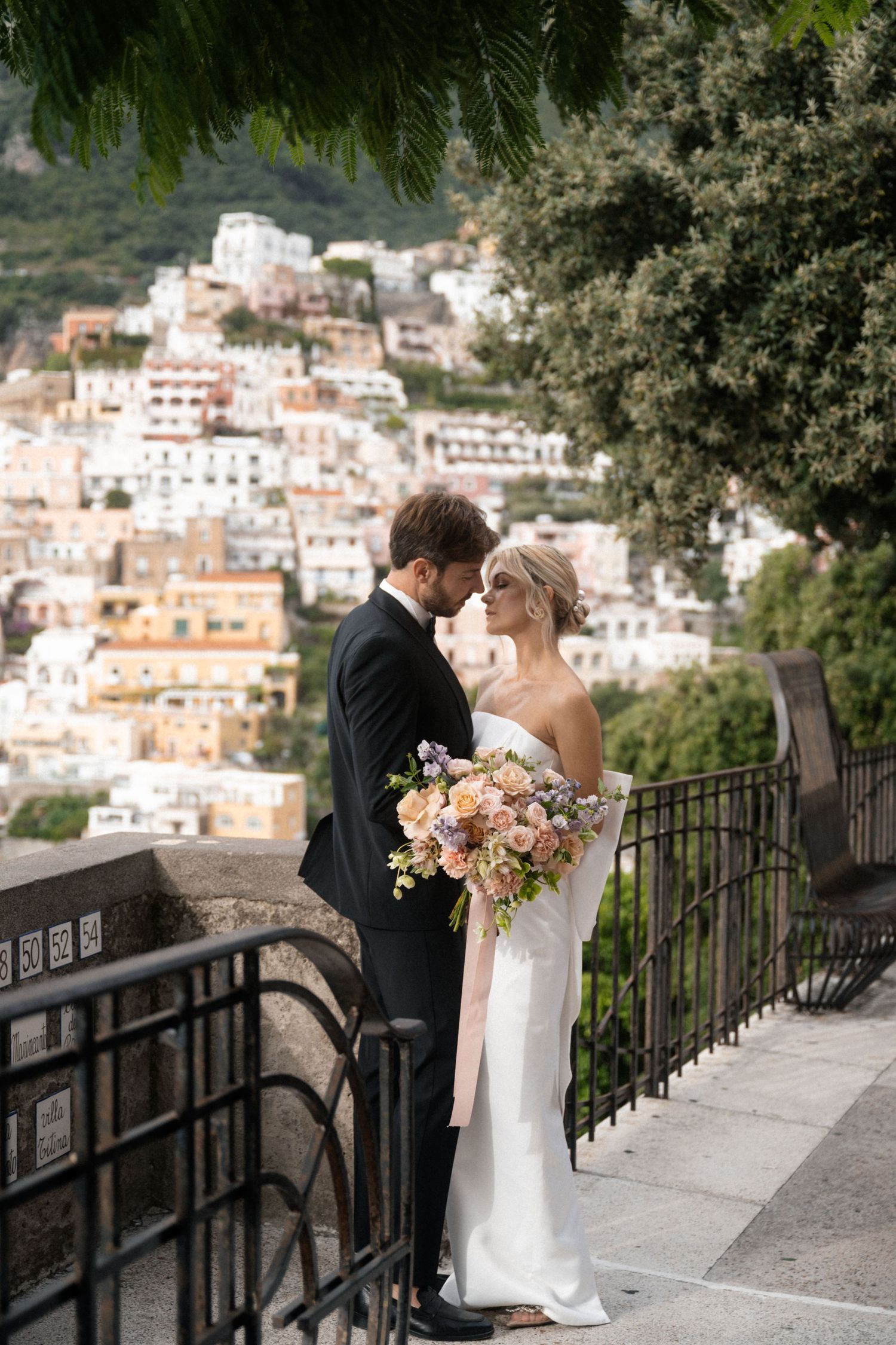 A couple shares a tender moment overlooking the stunning hillside village of Positano, Italy.