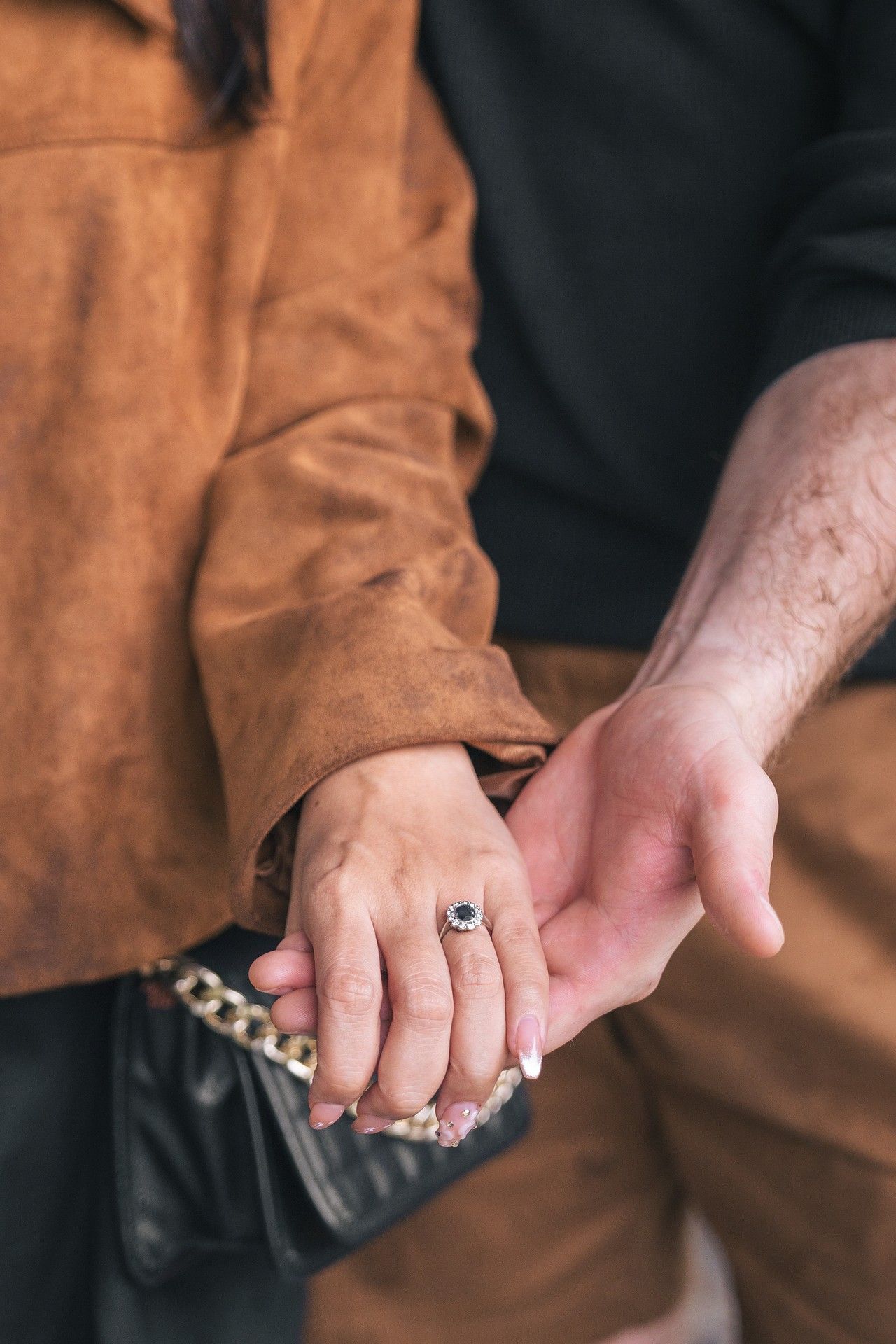 Close-up view of hands holding a black leather wallet in a brown jacket pocket.