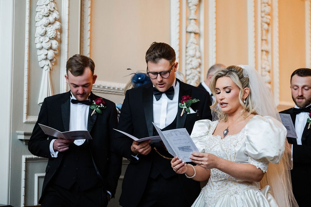 Wedding party members in formal attire share lighthearted moments while checking their phones before the ceremony.
