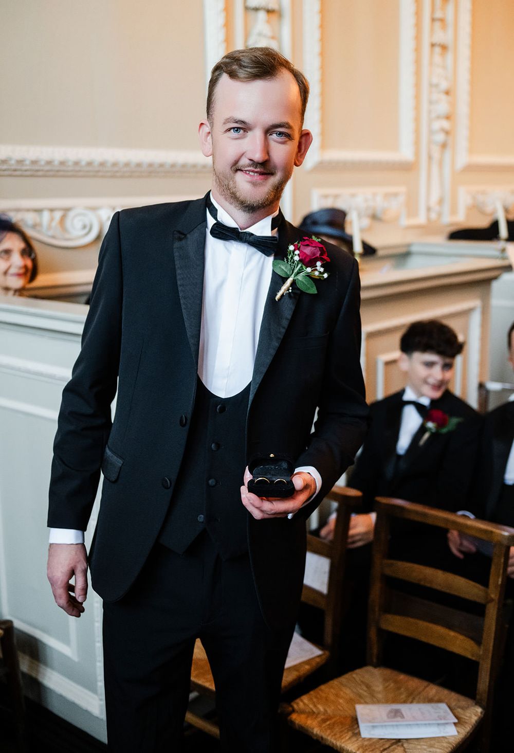 A sequence of candid moments showing groomsmen in black tuxedos laughing and sharing jokes in an elegant church setting.