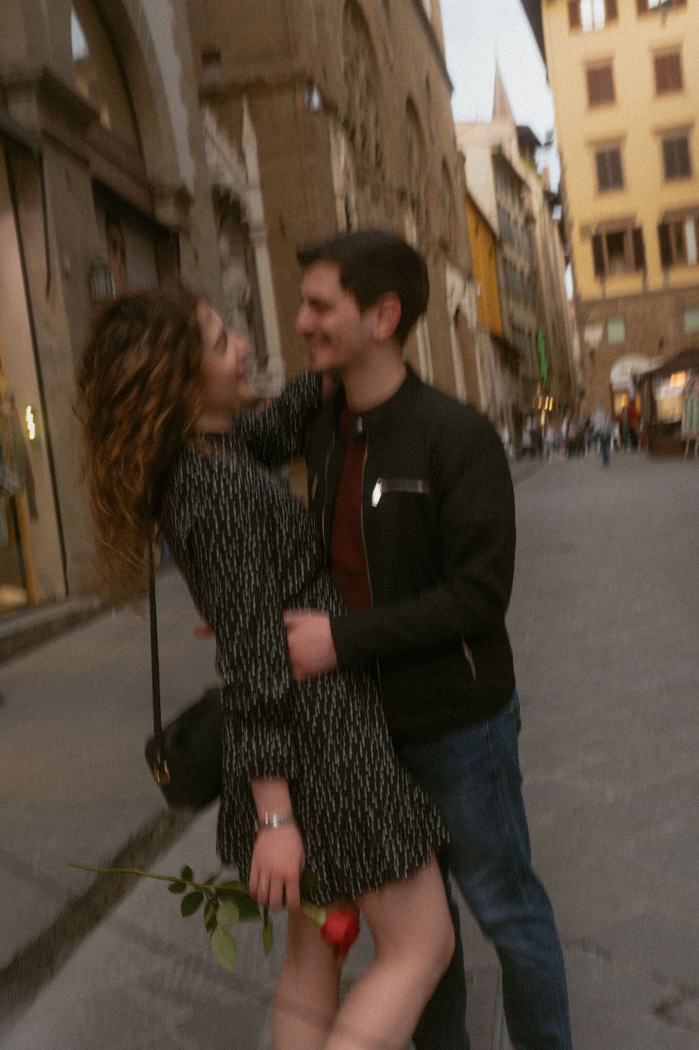 Couple embracing on a historic Florentine street with warm-toned buildings in background.