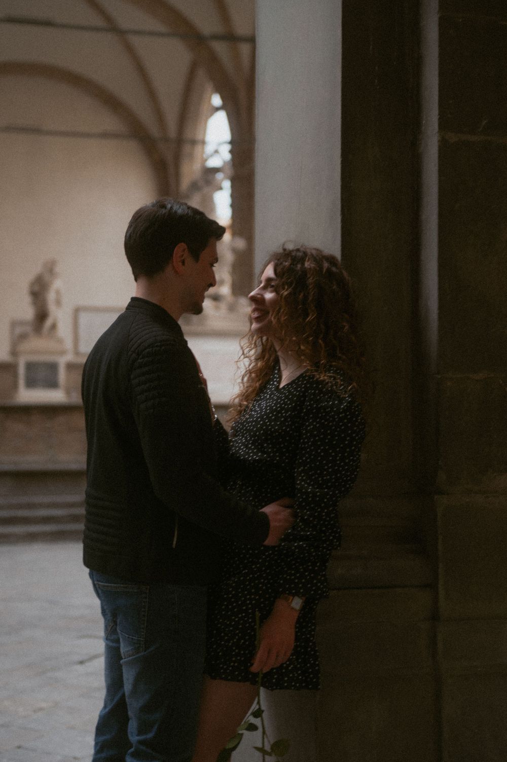 A romantic moment shared between two people beneath classical stone architecture.