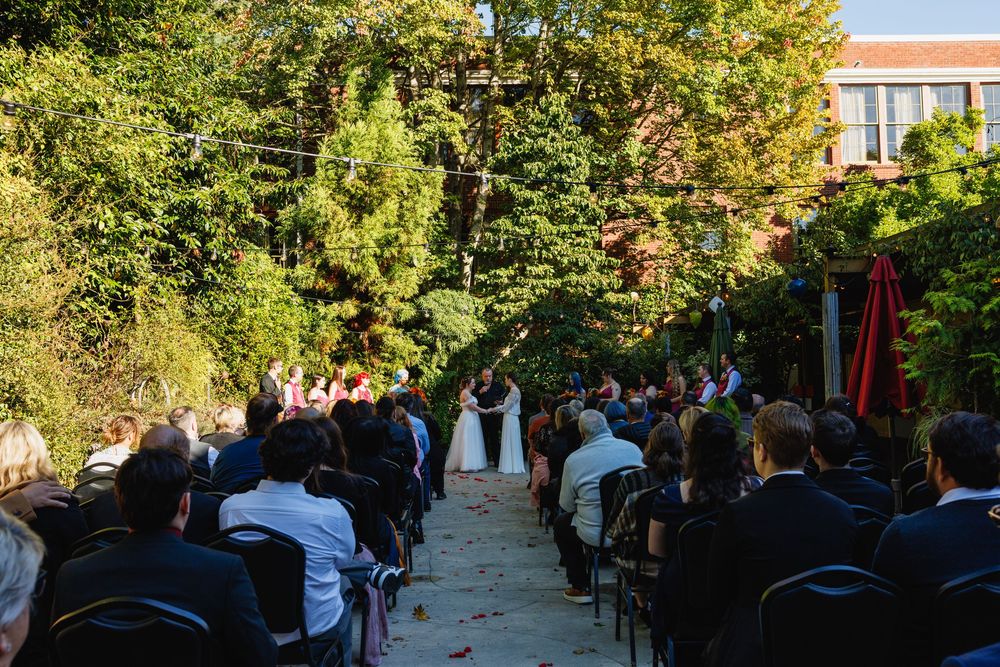 Wide shot of guests seated at an outdoor garden wedding ceremony with couple at the altar.