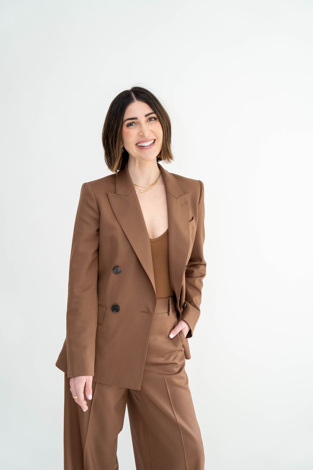 Professional brown power suit with double-breasted blazer and wide-leg trousers against white background.