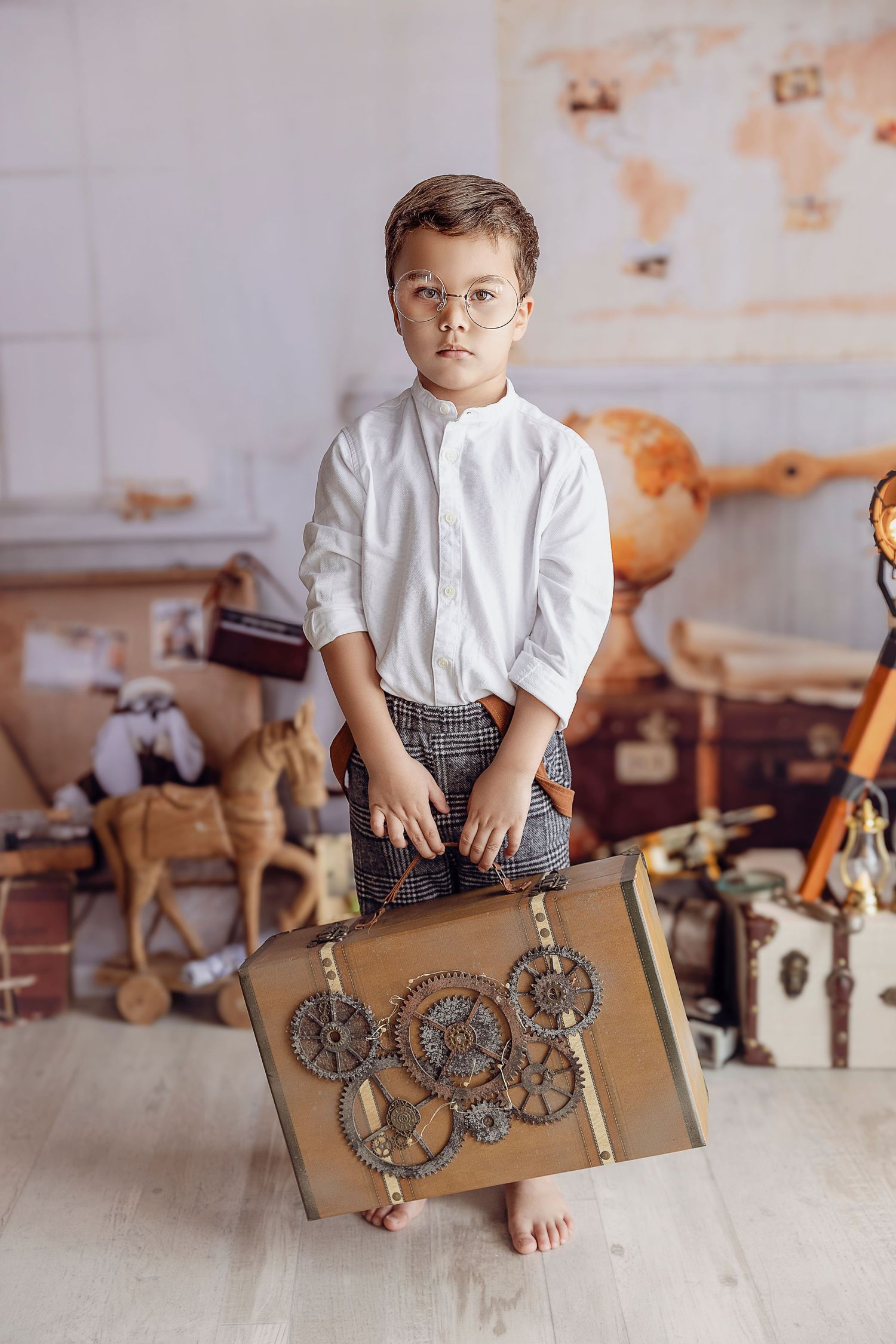 Nino de 5 anos posa aguantando una maleta estilo steampunk antiguo