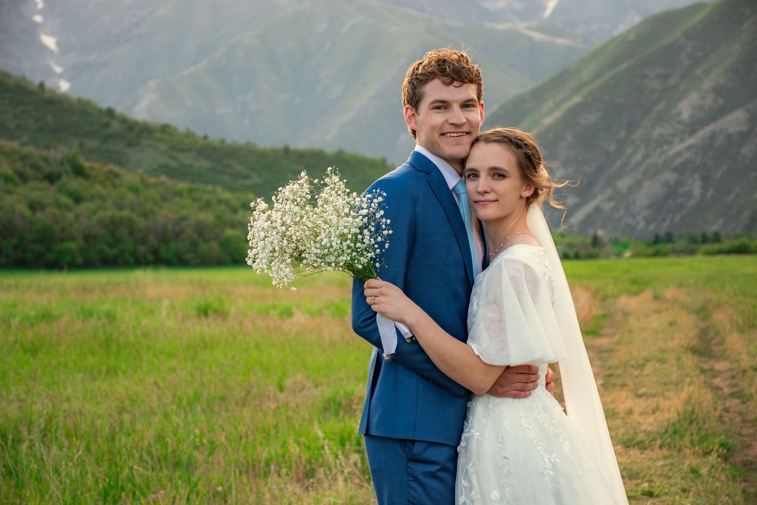 Bride and groom takes romantic photos in mountain meadow with dramatic sunset lighting in Utah.