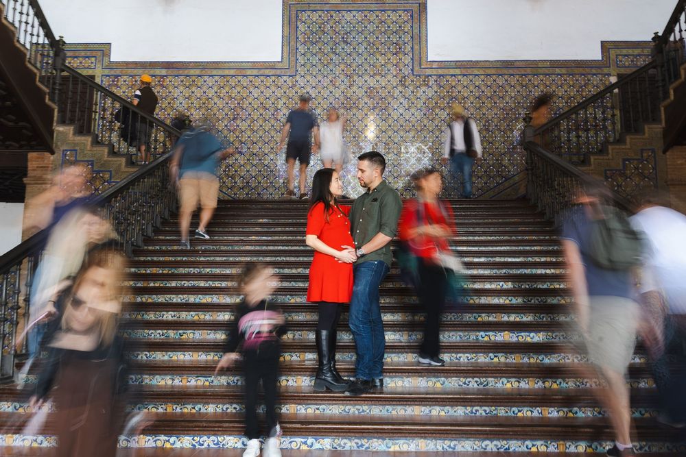 Long exposure photo on ornate tiled staircase shows motion blur of people walking while three figures remain still in center.