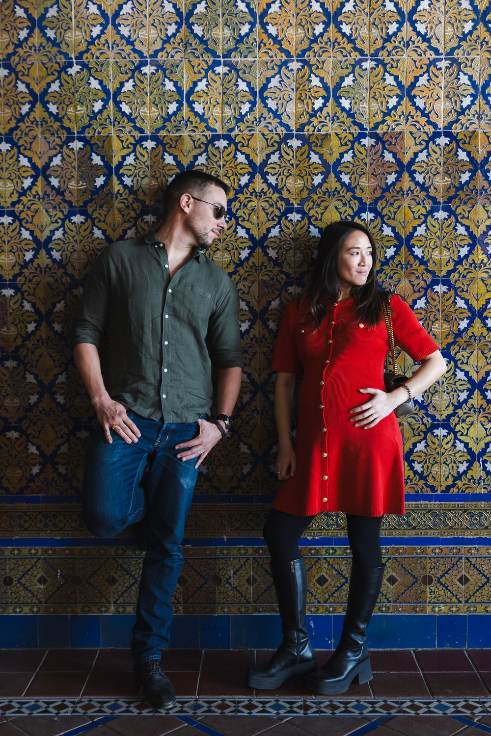 Couple poses against ornate blue and gold tiled wall in a series of artistic engagement photos.