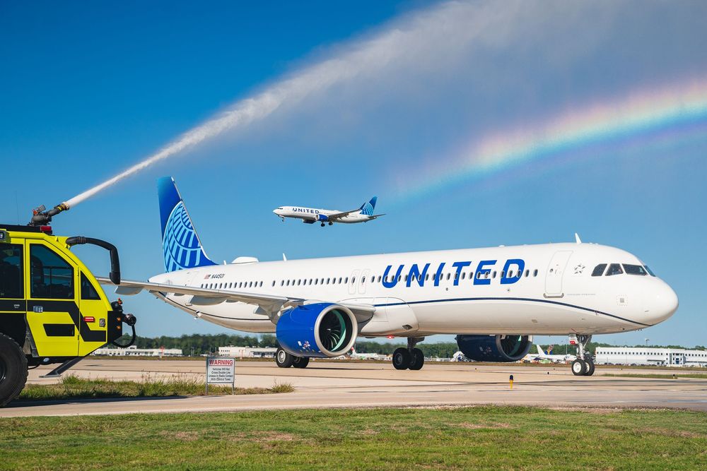 United Airlines plane receiving traditional water cannon salute on airport tarmac.