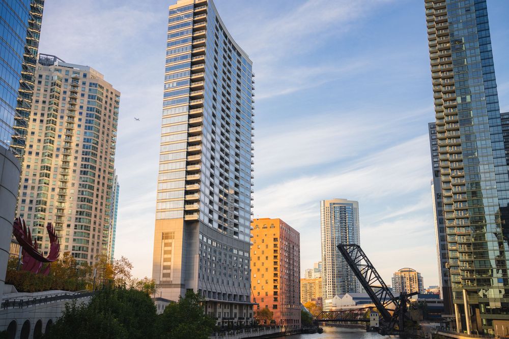 Modern glass skyscrapers reflecting sunlight against a blue sky in an urban downtown setting.