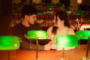 Vintage green glass banker's desk lamps illuminate a dark room creating an atmospheric ambiance.