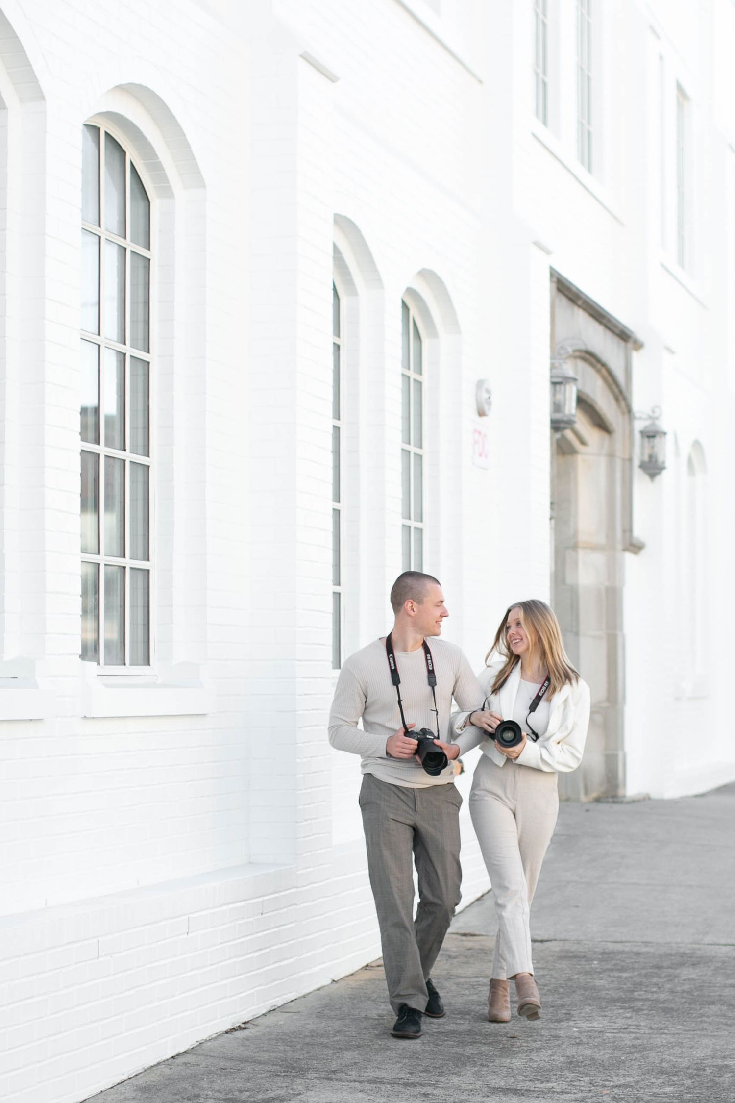 Julia and Sean walking together with cameras, husband and wife wedding photographers in Ohio.