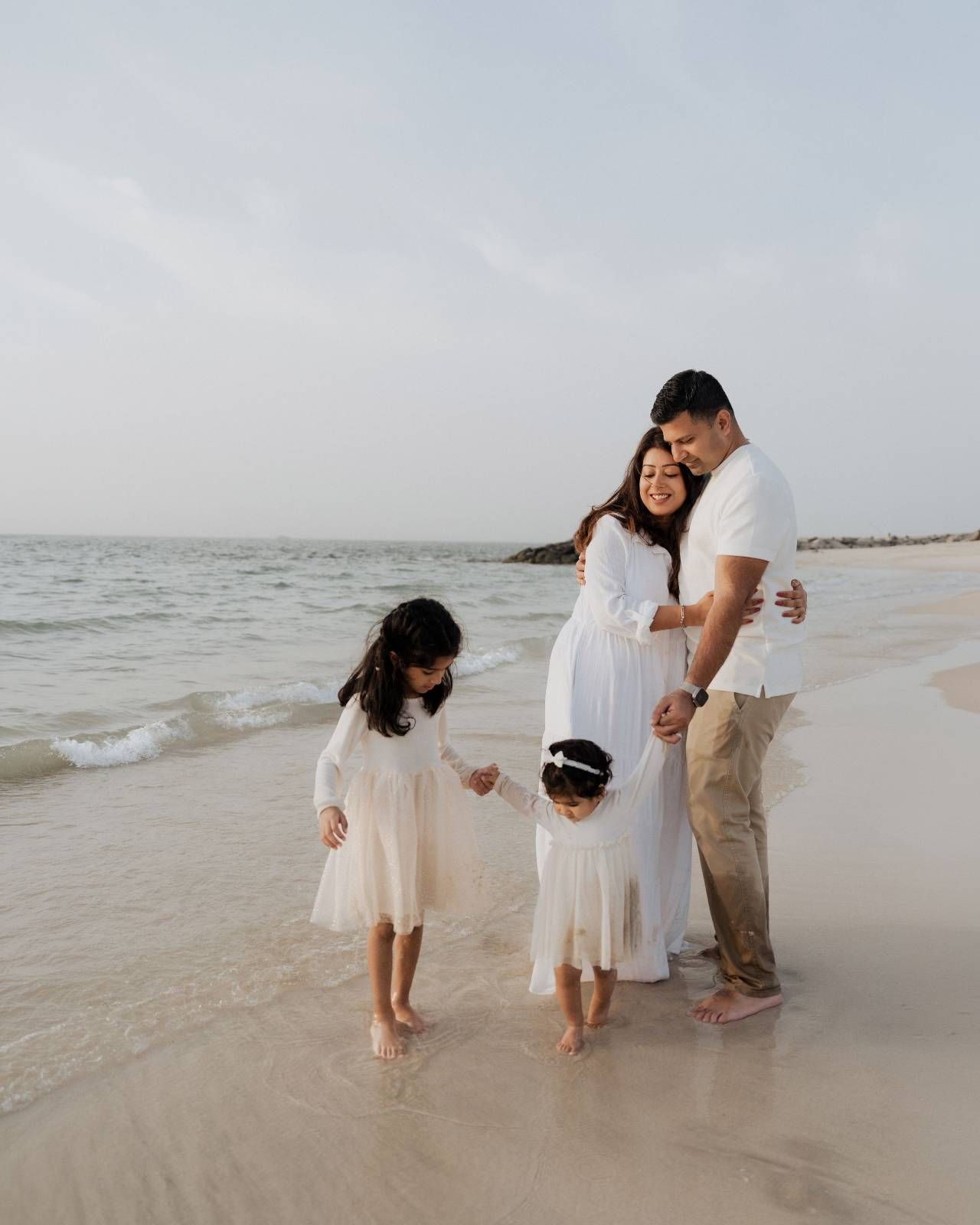 Parents and children walking together on beach shore in white family outfits