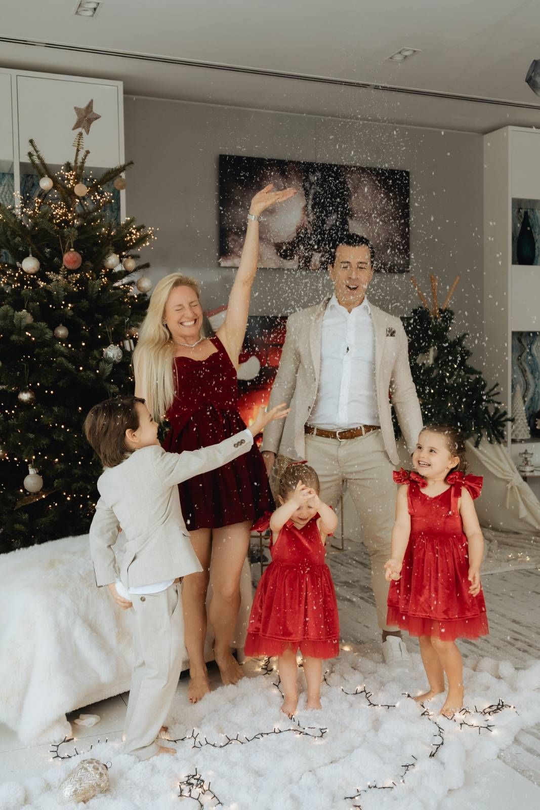 Family in holiday attire posing with Christmas tree and decorations indoors