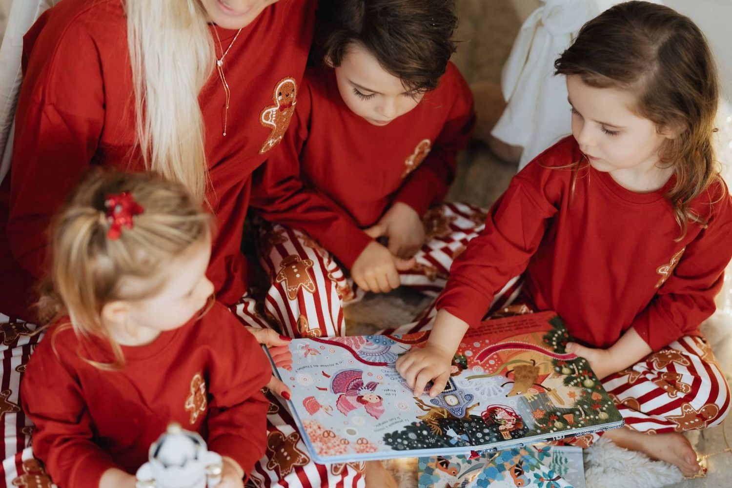 Children in red holiday outfits playing with Christmas gifts together