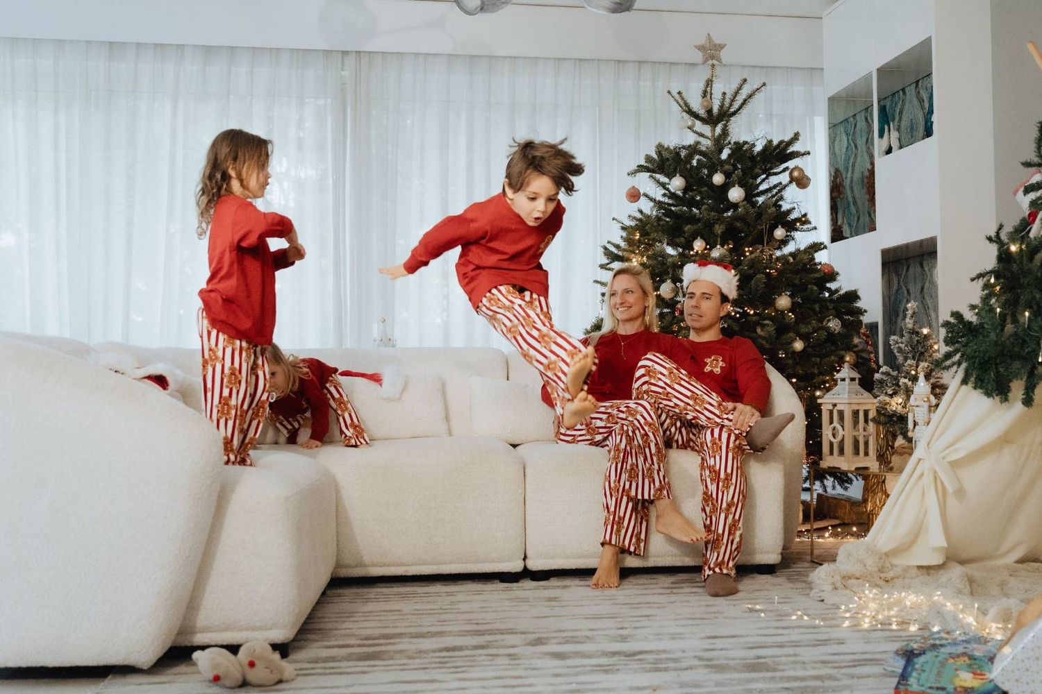 Family enjoying holiday fun with Christmas tree and presents on living room sofa