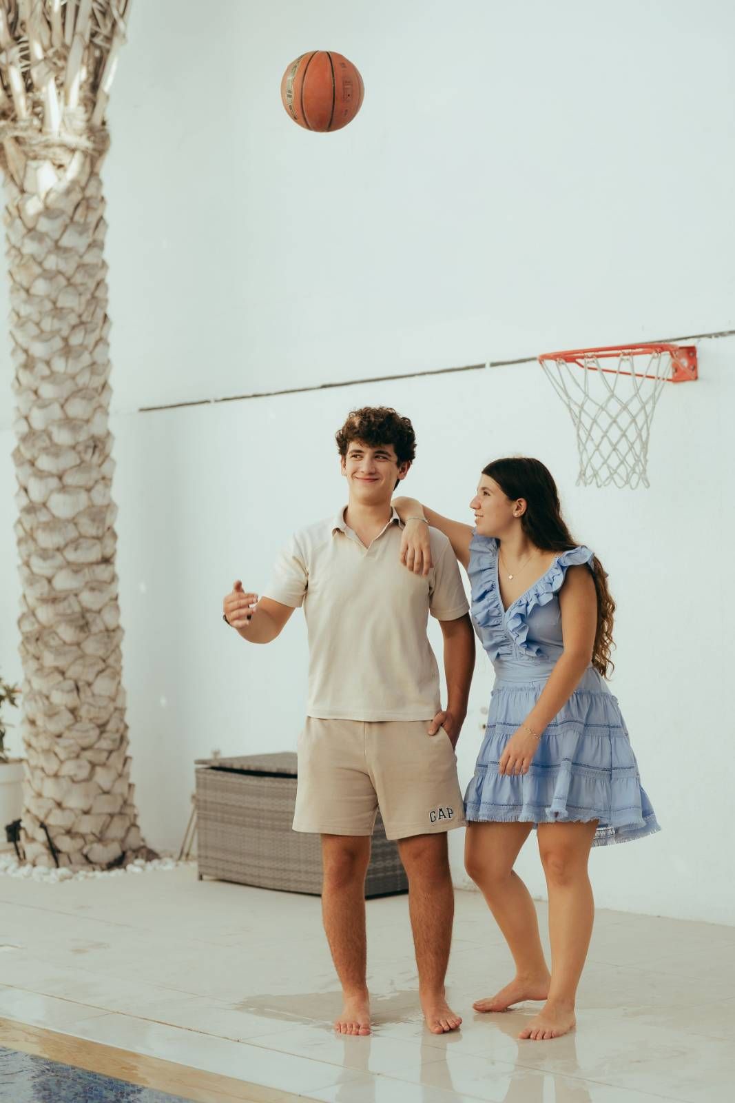 Family children playing basketball together indoors with beige and white clothing