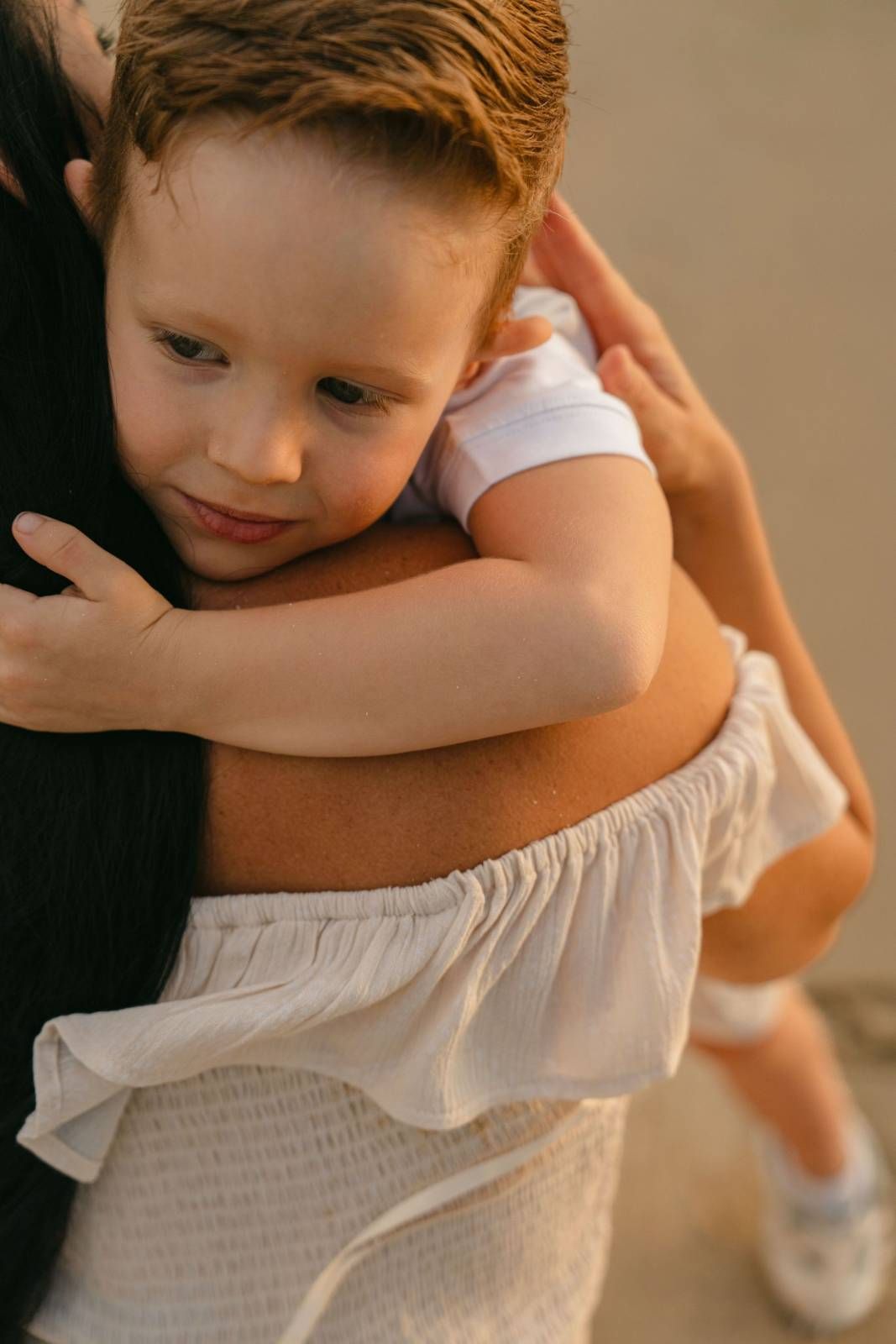 Sweet toddler resting peacefully wrapped in parent's embrace indoors