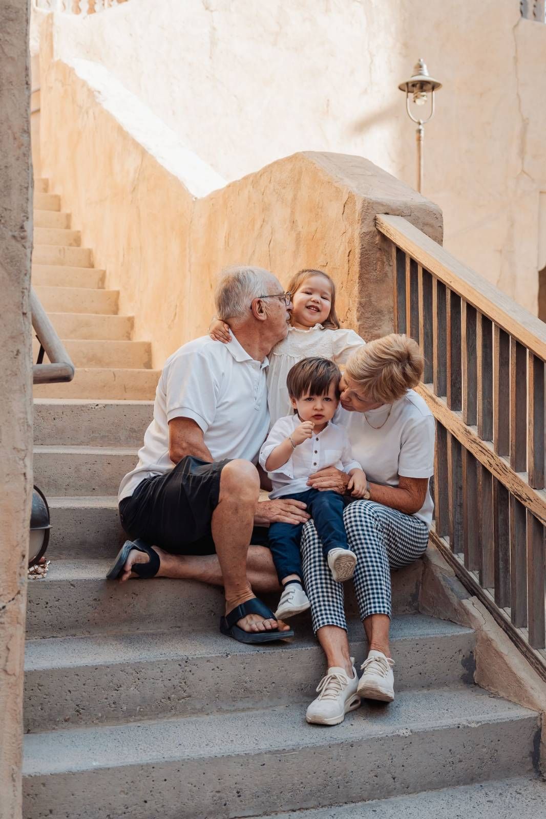 Family with children sitting on outdoor stairs in natural sunlit setting